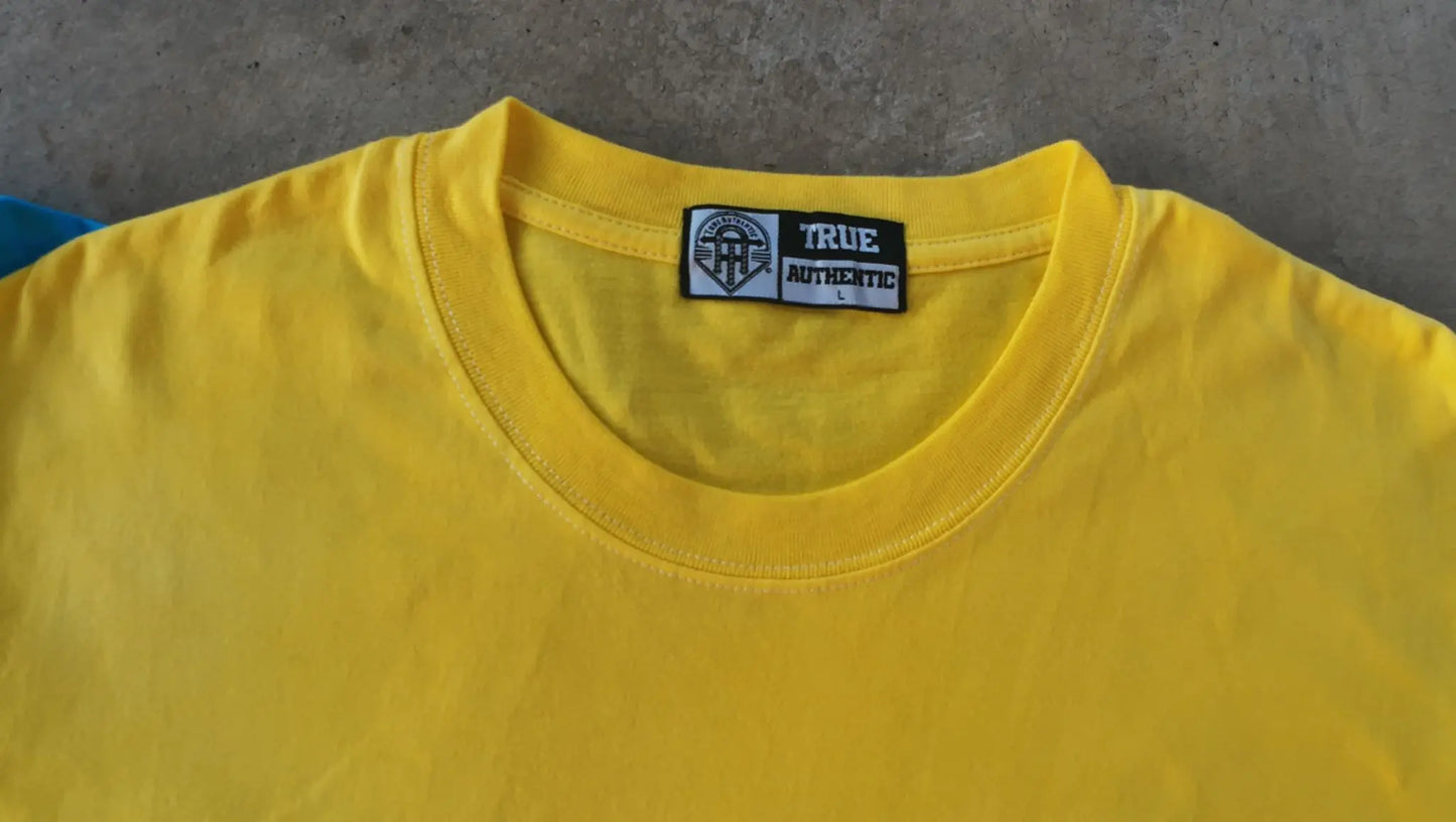Yellow t-shirt with a brand label on a gray surface