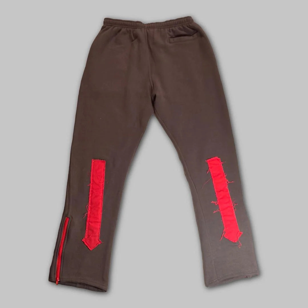 Front view of grey True Authentic technical sweatpants featuring red ankle zippers and signature logo embroidery on the thigh.
