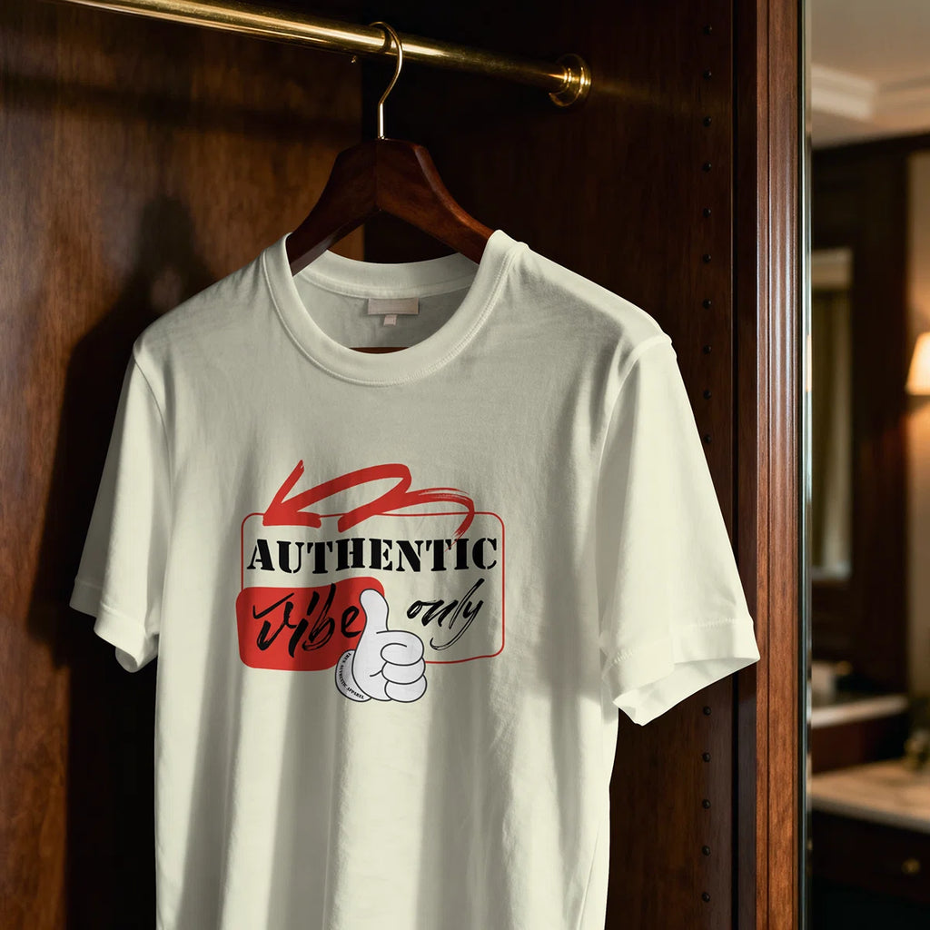 White t-shirt with red and black graphic design hanging on a wooden hanger against a wooden door.