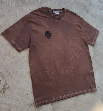 Brown t-shirt with a logo on a concrete floor