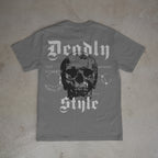 Gray t-shirt with a skull design and text on a concrete floor