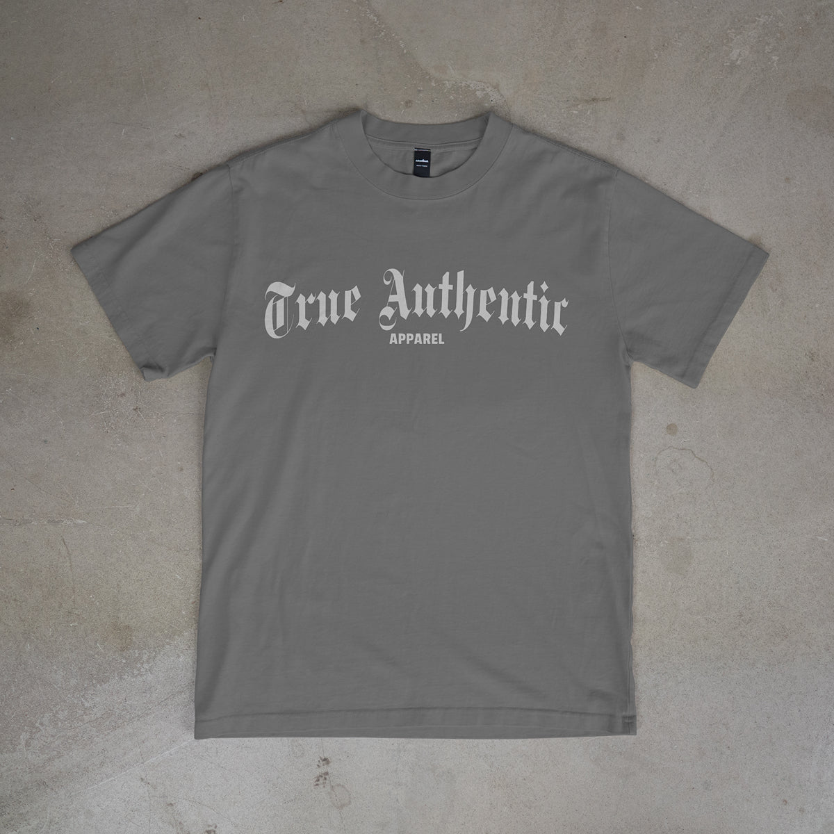 Gray t-shirt with 'True Authentic Apparel' text on a concrete floor