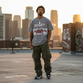 Man wearing a 'Money' t-shirt on a rooftop with cityscape in the background