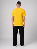 Person wearing a yellow t-shirt and black pants on a white background