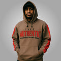 Man wearing a brown hoodie with red sleeves and 'True Authentic' text on a gray background