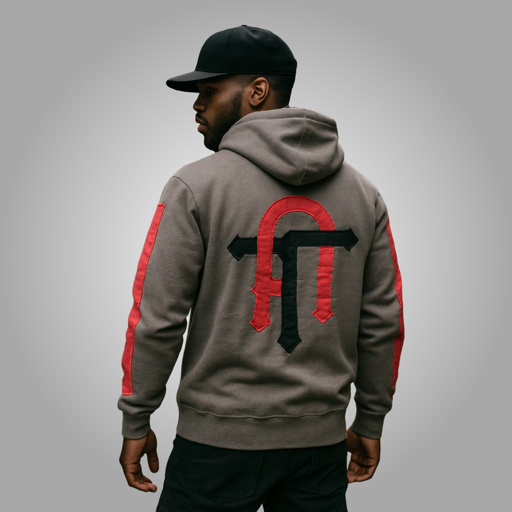 Person wearing a gray hoodie with red and black designs on a gray background