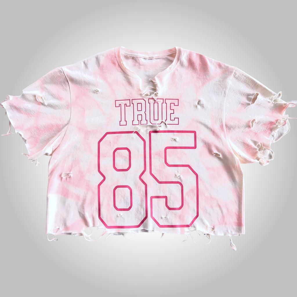 Pink tie-dye crop top with 'TRUE 85' text on a gray background