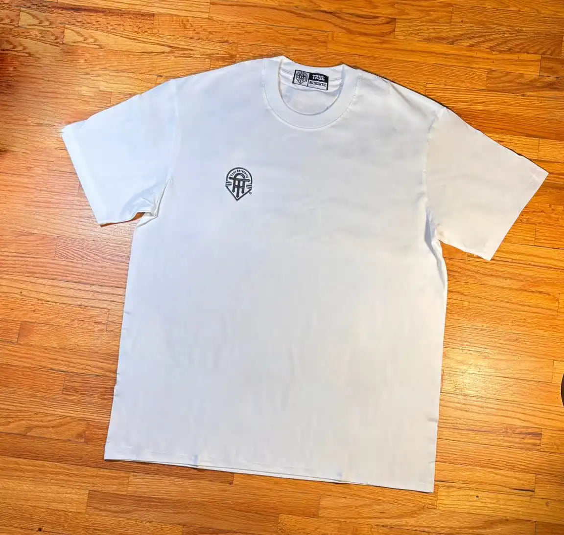 White t-shirt with a black logo on a wooden surface