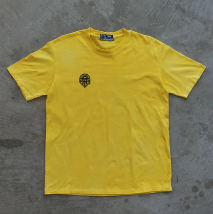 Yellow t-shirt with a black logo on a gray concrete surface