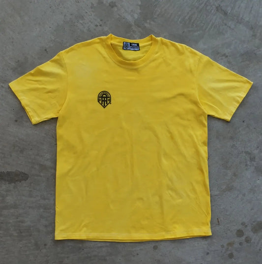 Yellow t-shirt with a black logo on a gray concrete surface