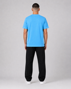 Person wearing a blue t-shirt and black pants on a gray background