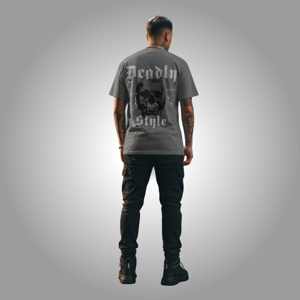 Person wearing a gray t-shirt with a skull design and text on the back, standing against a gray background.
