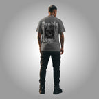 Person wearing a gray t-shirt with a skull design and text on the back, standing against a gray background.