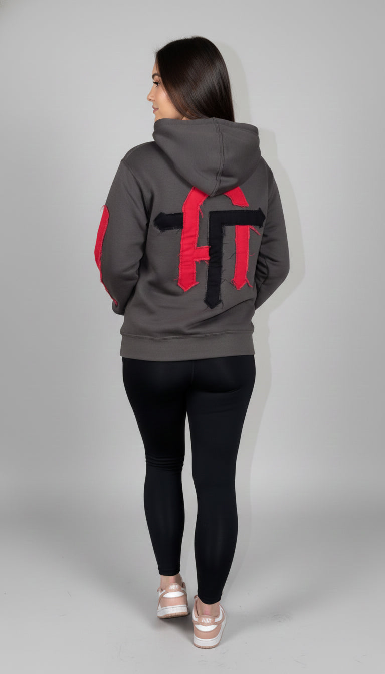 Person wearing a gray hoodie with red and black designs on a gray background