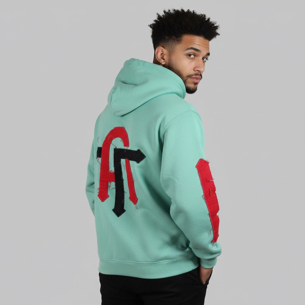Person wearing a light blue hoodie with red and black designs on the back against a gray background