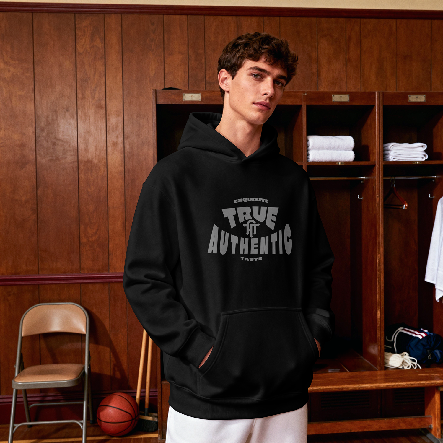 A male model wearing the black True Authentic Exquisite Taste hoodie in a vintage wood-paneled locker room setting.