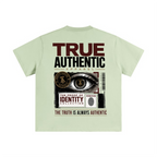 A light sage green short-sleeve t-shirt shown from the back, featuring a large graphic print with the text 'TRUE AUTHENTIC APPAREL' and a collage of an eye, a fingerprint, and security badge elements.