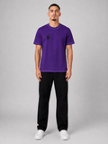 Man wearing a purple t-shirt and black pants on a gray background