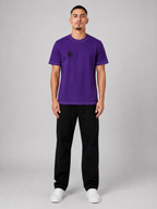 Man wearing a purple t-shirt and black pants on a gray background