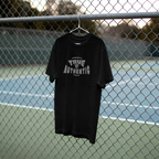 Black t-shirt with 'True Authentic' text on a hanger against a chain-link fence background.