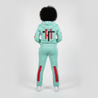 Person wearing a mint green tracksuit with red accents on a white background