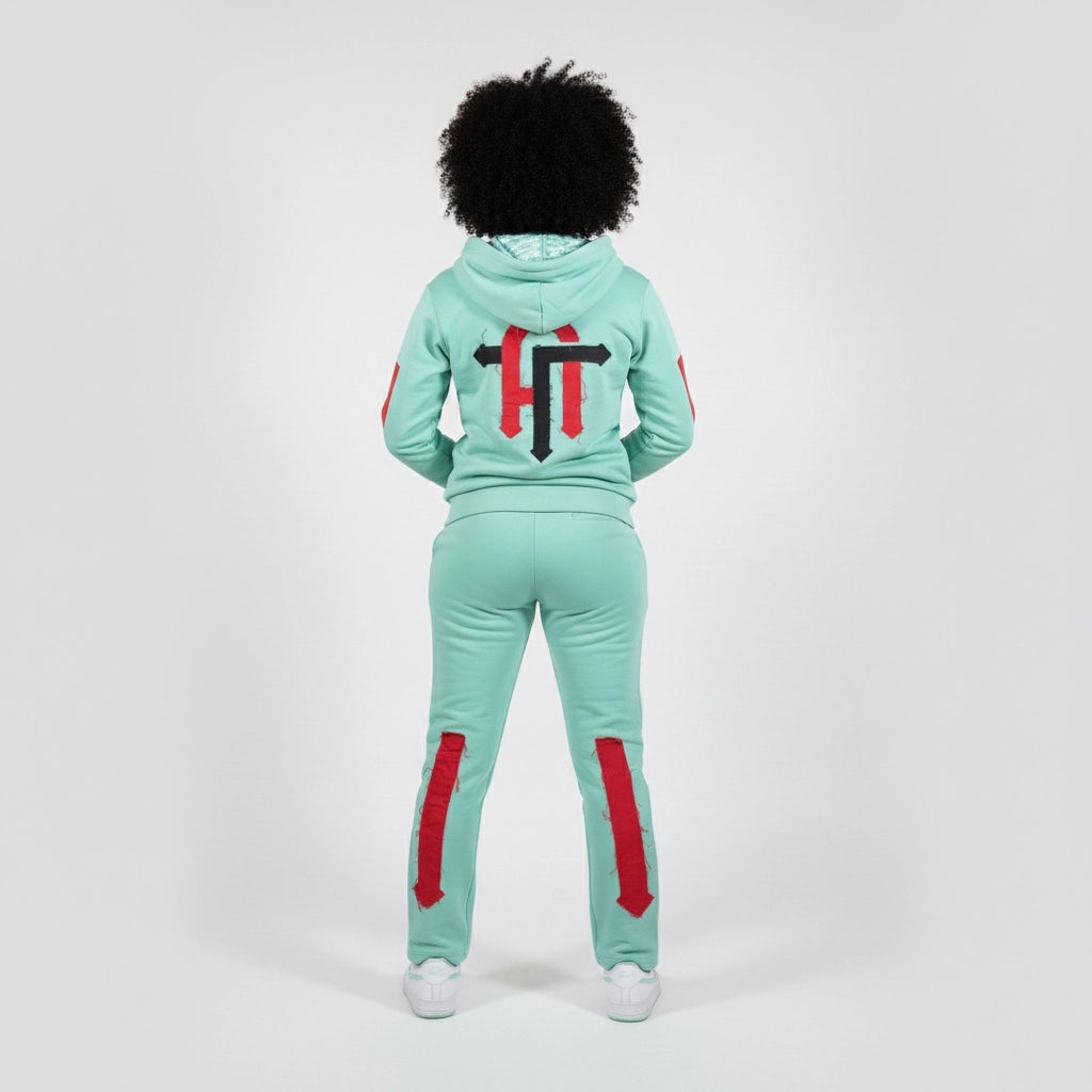 Person wearing a mint green tracksuit with red accents on a white background