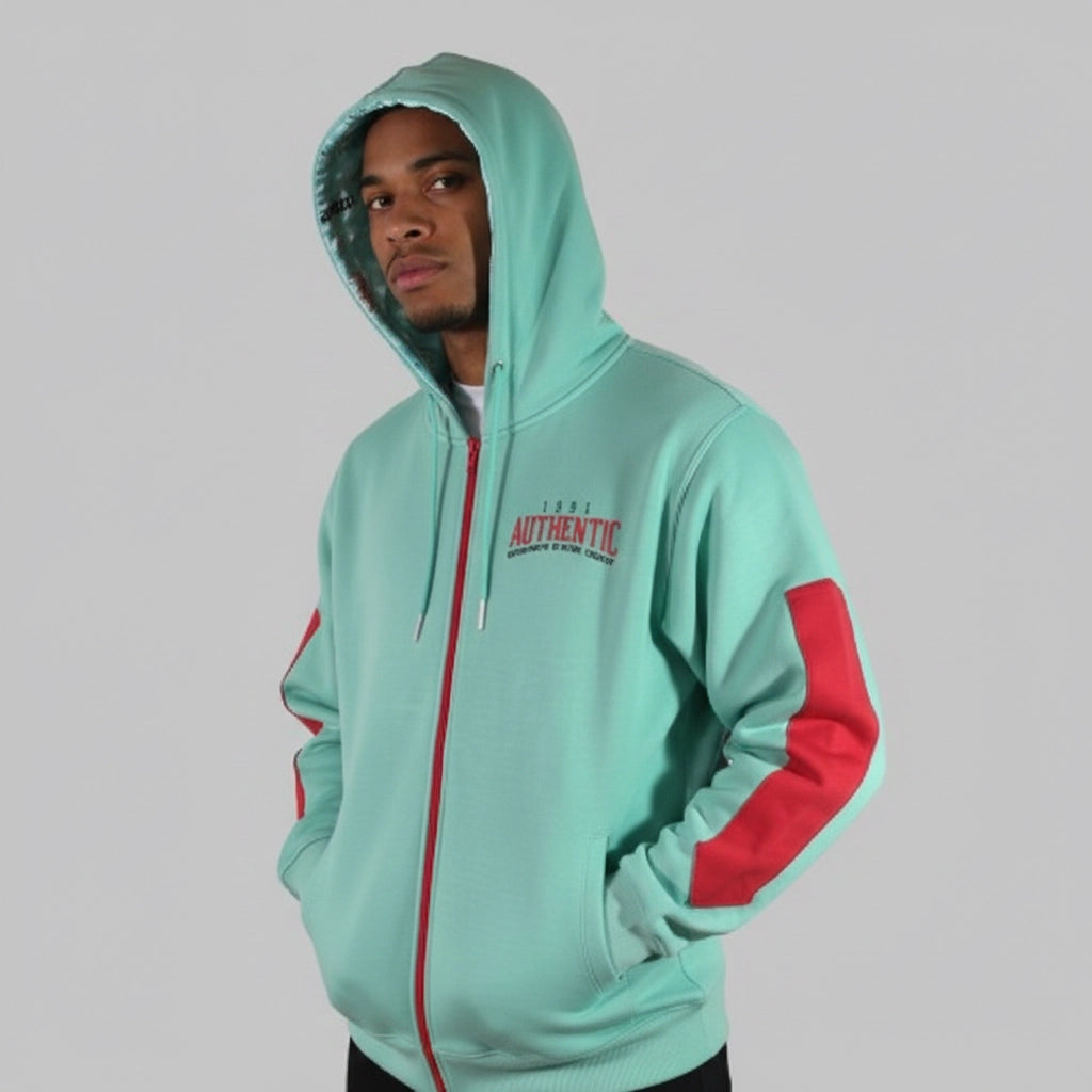 Person wearing a light blue hoodie with red accents on a gray background