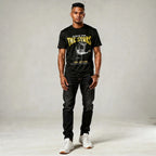 Man wearing a black t-shirt with graphic design and text, standing against a plain background