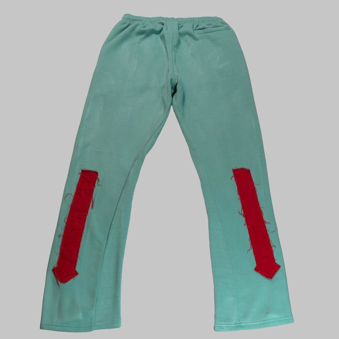 Teal pants with red patches on a gray background