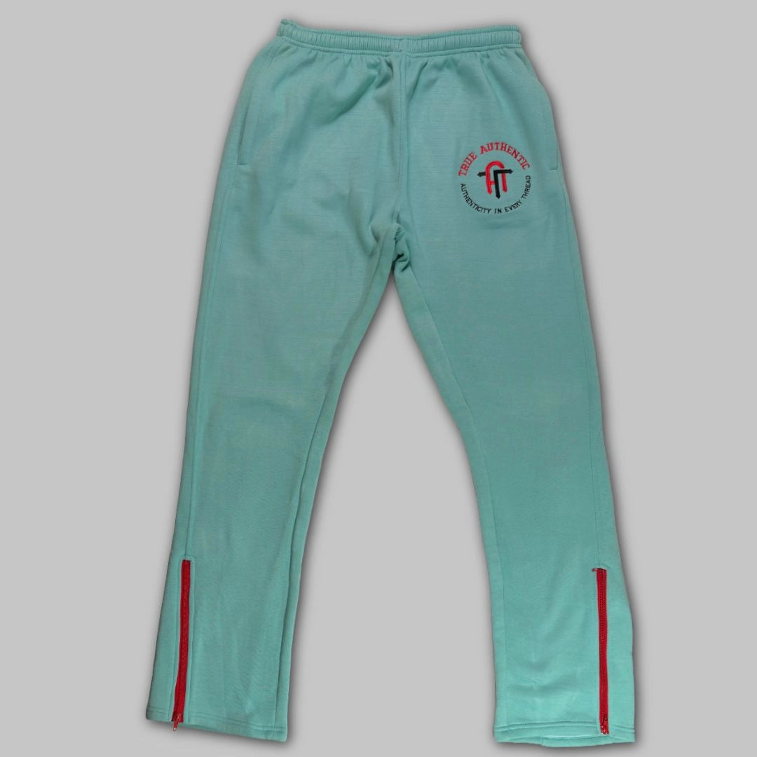 Teal tracksuit pants with a logo on a gray background