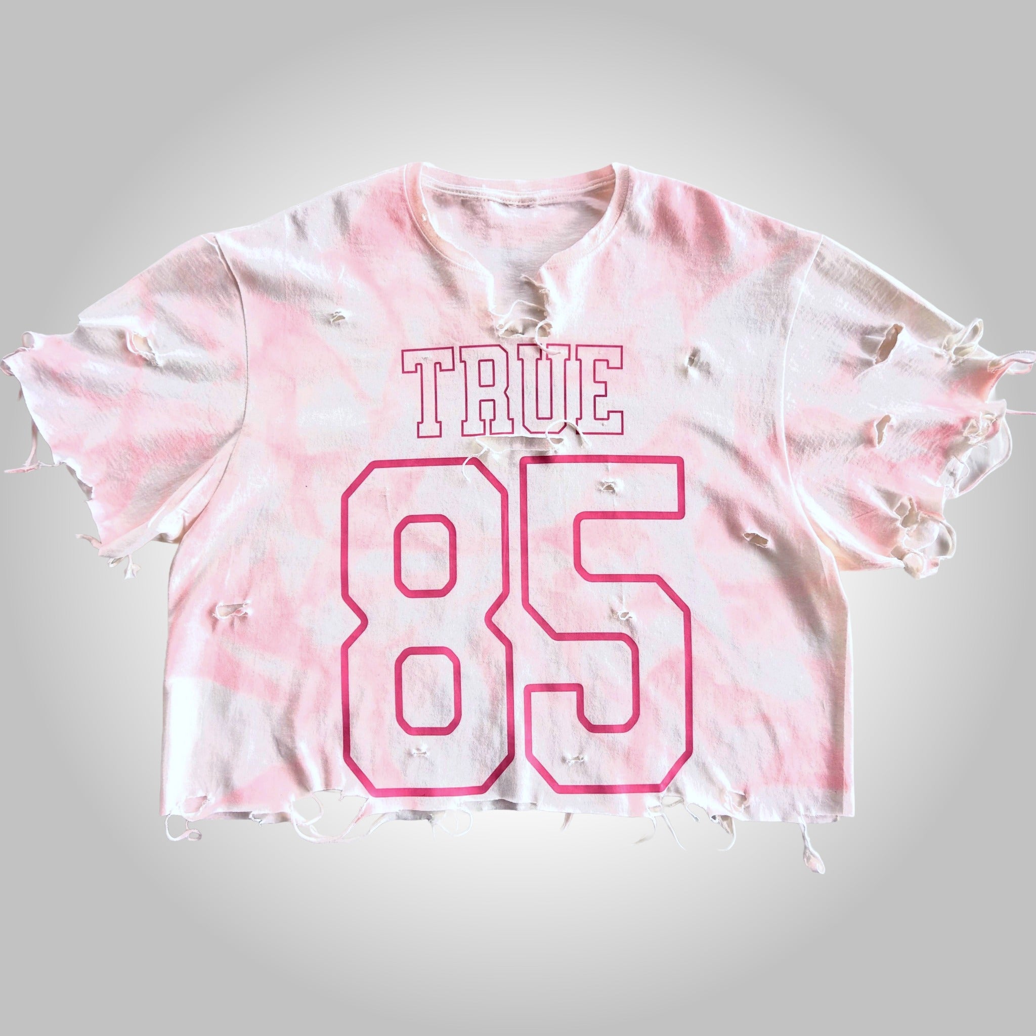 Pink tie-dye crop top with 'TRUE 85' text on a gray background