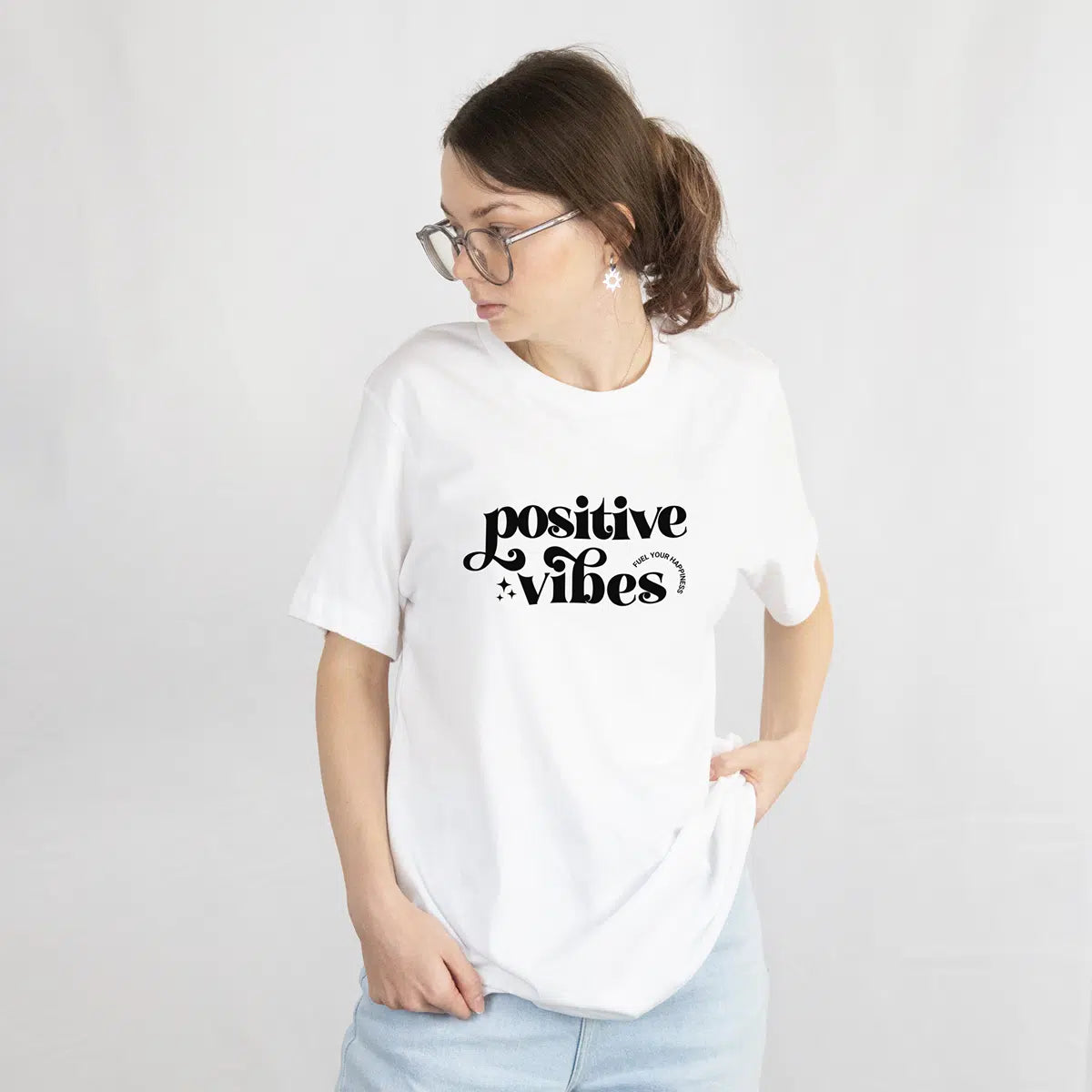 Person wearing a white t-shirt with 'positive vibes' text on a plain background