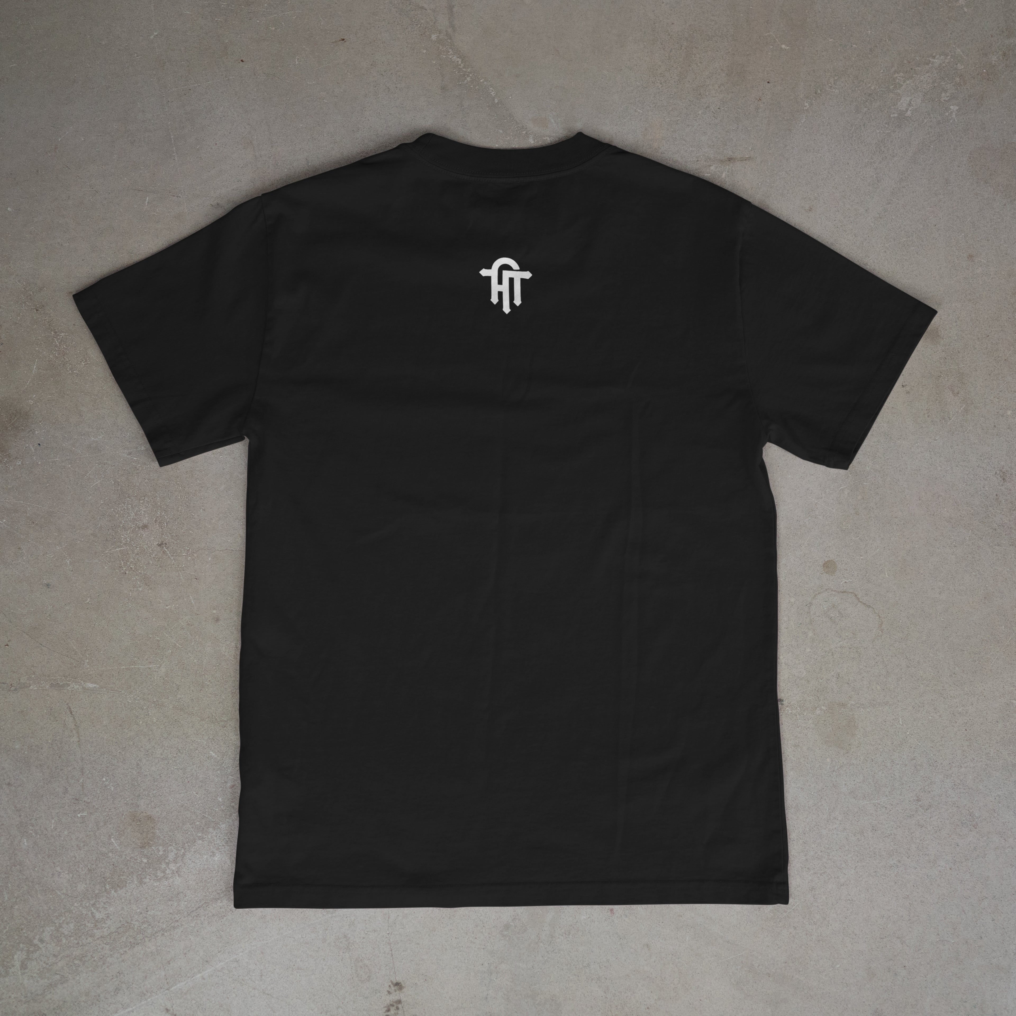Black t-shirt with a white logo on the chest, laid flat on a gray surface.
